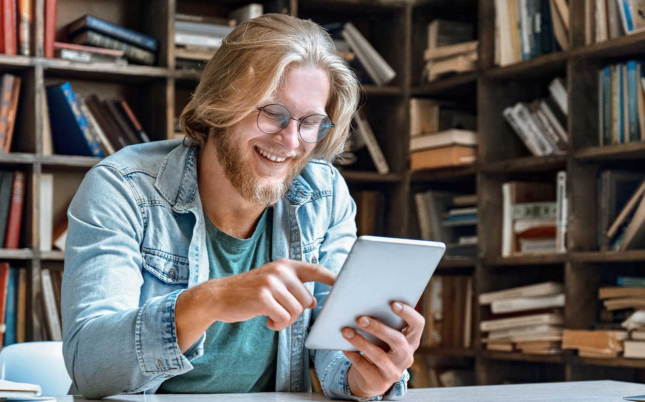 Ein Mann mit Tablet sitzt am Tisch.